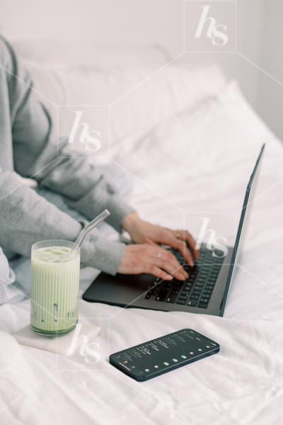 Woman typing on laptop as she works from bed, part of Matcha Time: green workspace stock photos & videos collection