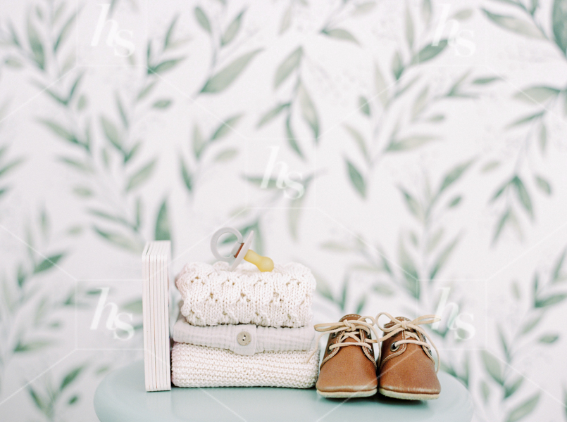 Baby book, shoes, clothes, and soother piled neatly next to each other, part of Nursery baby stock photos collection