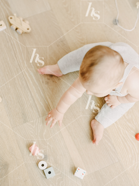 Baby reaching for paper fan in baby clothing flatlay scene, part of Nursery: baby stock photos