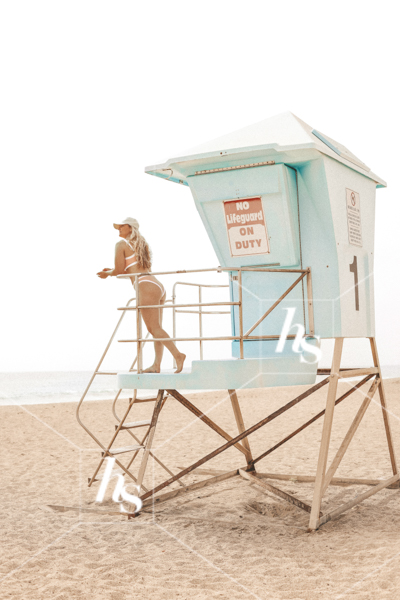 stock image of Woman in pink bikini hanging out at the lifeguard's hutpart of Beach Babe collection, costal stock photos & videos perfect for summer travel enthusiasts.