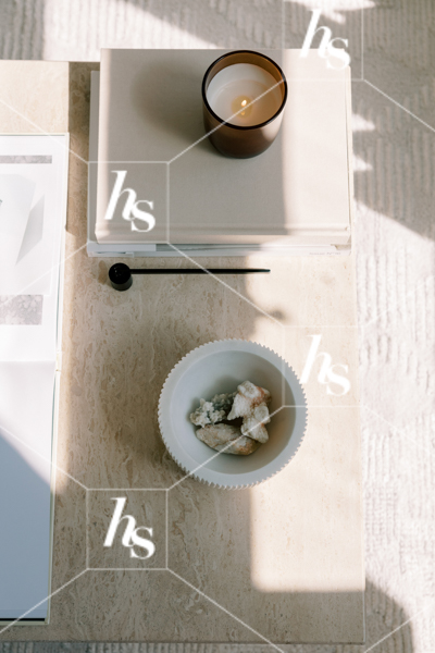 A flatlay of a styled coffee table, with a lit candle and a bowl full of gems, part of Blank space collection of workspace & interior stock imagery