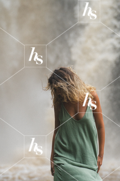 A woman in a flowing green dress standing near misty water, evoking calm and freedom. Inspiring self-care and travel imagery.