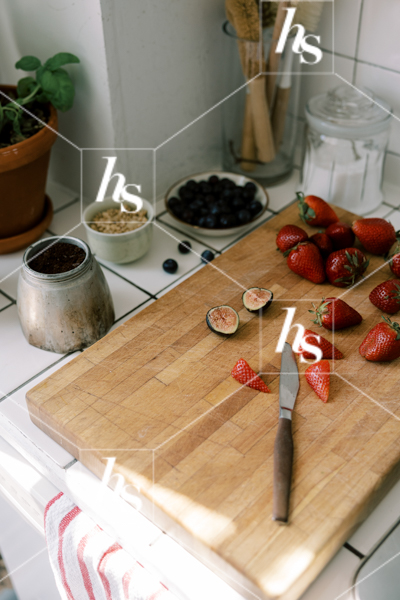 chopping fresh strawberries and figs for breakfast in a bright kitchen. Wellness stock photos for nutrition content, lifestyle bloggers, and mindful living brands.