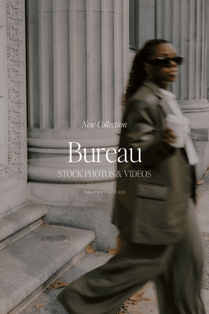 A stylish woman walks past grand stone pillars wearing an oversized blazer and sunglasses, embodying the refined dark academia business aesthetic from Haute Stock’s Bureau collection.